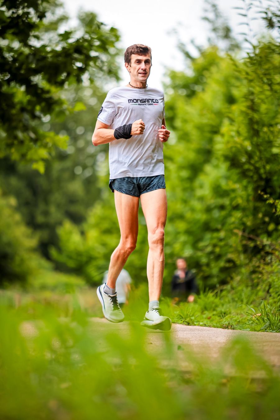 Stas Nikitin running on a path between green trees